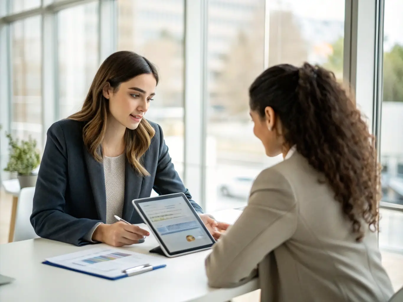 A consultant demonstrating a technology solution to a client, showcasing a software interface on a tablet in a collaborative meeting.
